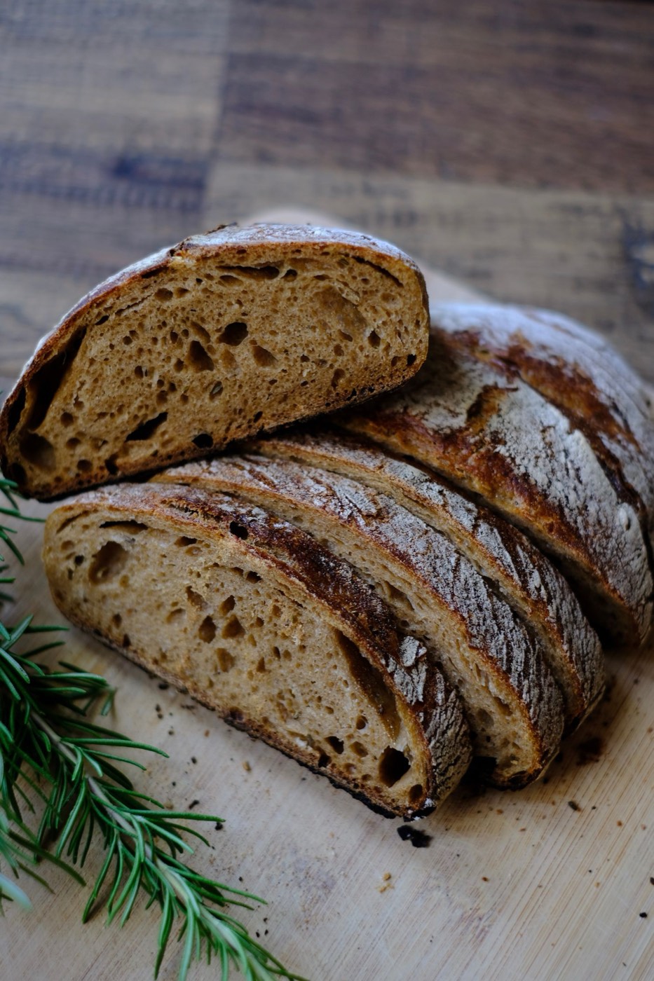Pagnotte di pane rustico con crosta scura, tagliate su un tagliere di legno